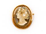 Une broche en or représente le profil d'une femme.