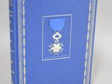un vieux livre avec une couverture bleue sur laquelle est apposée une médaille