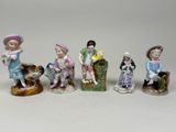 several figurines of children sitting on a bench with a dog