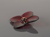 a close up of a red flower brooch on a reflective surface