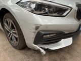 the front end of a silver bmw car with a denting front bumper