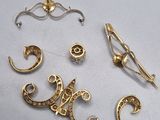 three gold brooches and a pair of scissors on a white surface