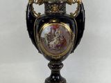un vase noir et doré sur lequel est représentée une femme
