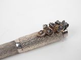 a silver pen with flowers on it on a white surface
