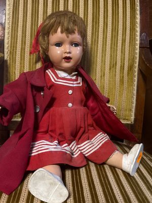 une petite poupée assise sur une chaise dans une pièce