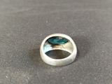 silver ring with a green stone in the center on a table