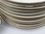 a stack of white plates with gold rims on a table