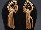 une paire de boucles d'oreilles en or ornées de franges sur un mannequin noir