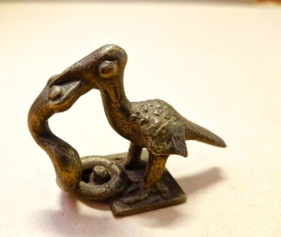 a bronze statue of a bird holding a fish in its beak