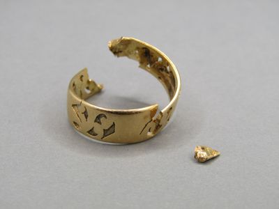 a close up of a gold ring on a table next to a small piece of gold