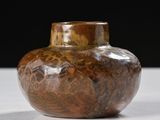 a brown vase sitting on a table with a black background