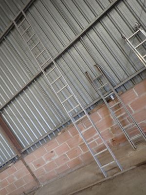 several ladders are leaning against a wall in an industrial building