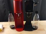 une cafetière rouge posée sur une table, à côté d'une bouteille d'eau
