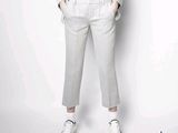 un homme en chemise blanche et pantalon gris qui pose pour une photo
