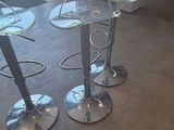 three clear plastic bar stools sitting on top of a carpeted floor