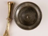 a metal bowl and a brass spoon on a white surface