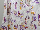 purple and yellow flowers on a white shirt hanging on a hanger