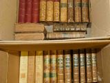 a cardboard box filled with old books on a shelf
