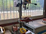 une table de perçage sur laquelle est posée une perceuse, dans un garage
