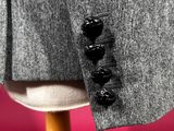 close up of a grey jacket with a black button on a mannequin