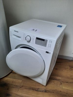a white washing machine sitting on the floor next to a water heater