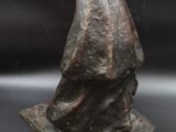 statue of a man sitting on a rock with a hat on his head