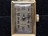 a close up of a gold watch on a black surface