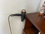 a hair dryer that is plugged into the wall next to a dresser