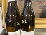 deux bouteilles de vin posées sur une table à côté d'un tableau