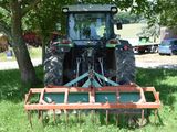 a tractor with a plow attached to it in the grass