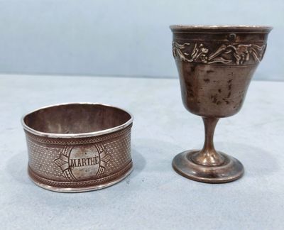 une paire de gobelets en argent et une coupe en argent posés sur une table