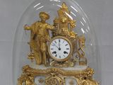 une horloge en or sous un dôme de verre sur une table