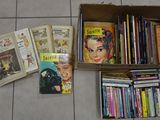 a box full of books on the floor next to a pile of books