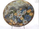 a plate with flowers painted on it sitting on a stand