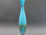 une image représentant un vase bleu à bord doré posé sur un socle blanc