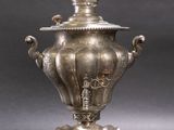 silver plated urn with handles on stand on grey background