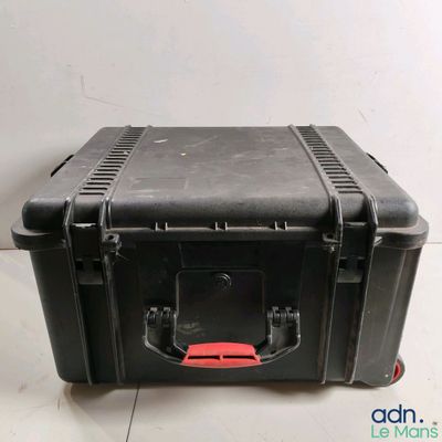 une valise noire avec une poignée rouge posée par terre