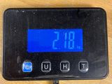 a digital clock on a wooden table with a charger