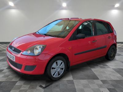 une Ford Fiesta rouge garée dans une grande pièce au sol à carreaux