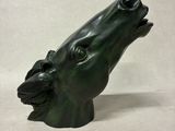 une sculpture verte représentant la tête d'un chien, la gueule ouverte