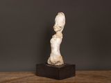 une statue blanche représentant une femme, posée sur une table en bois