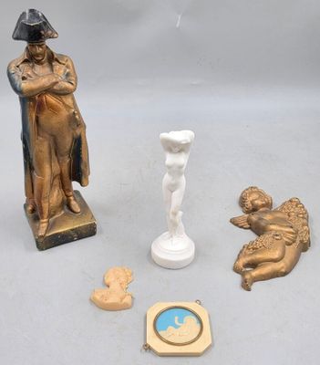 une statue représentant un homme tenant un bébé dans ses bras, à côté d'autres objets