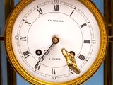 a gold clock with roman numerals and a blue background