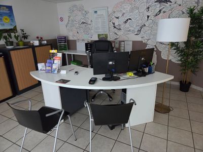une table blanche sur laquelle est posé un ordinateur portable, dans une pièce