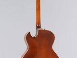 a brown acoustic guitar hanging from a white wall