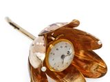 une petite fleur en or sur laquelle est représentée une horloge