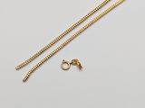 a gold chain and a pair of earrings on a white surface