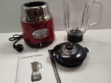 a red blender sitting on a table next to a book
