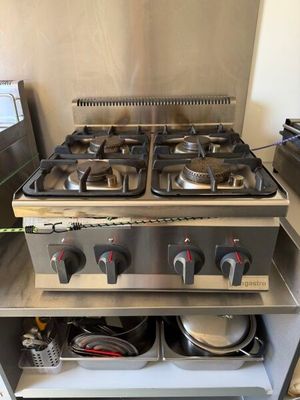 une plaque de cuisson argentée à trois feux sur laquelle sont posées deux casseroles