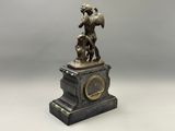 une image représentant une statue d'un homme tenant un chien dans ses bras, au sommet d'une horloge